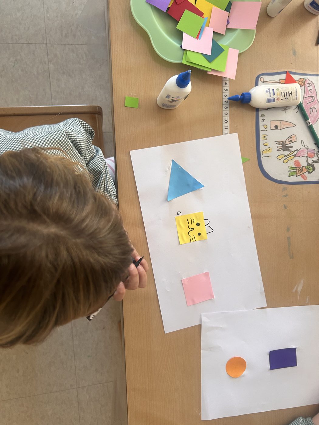Estudiante trabajando con figuras geométricas de colores sobre la mesa